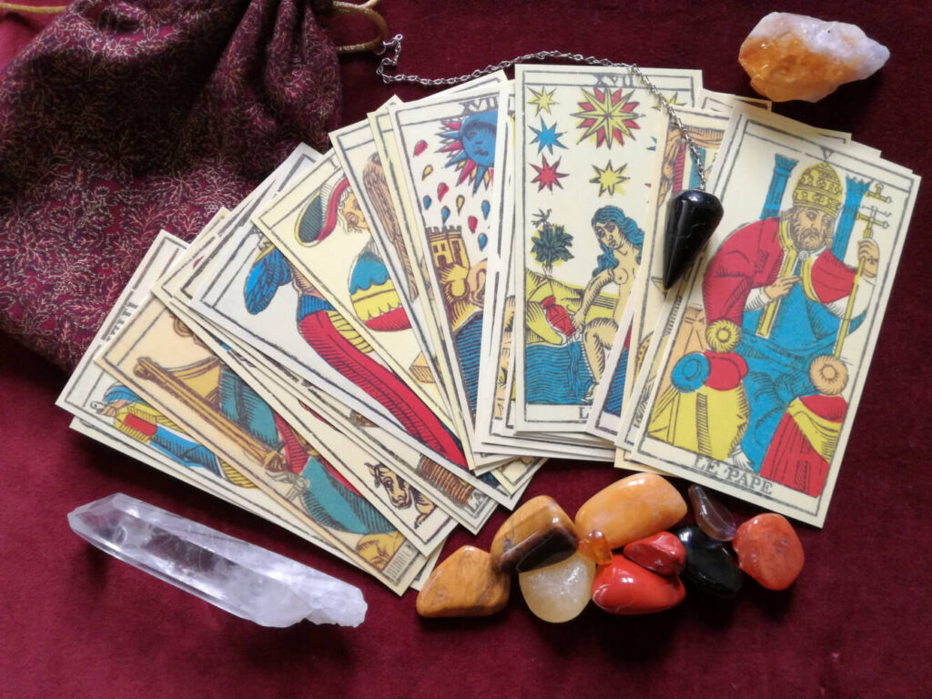 Tarot cards, crystals, and stones on burgundy cloth.  Tarot spread, divination.