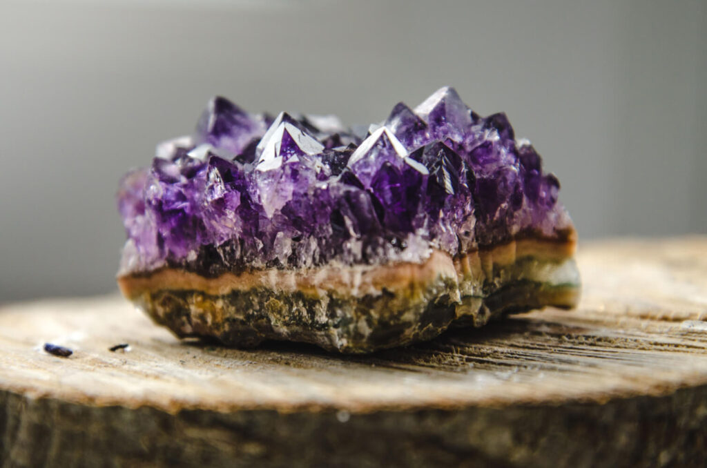 Purple amethyst crystal cluster on wooden surface.