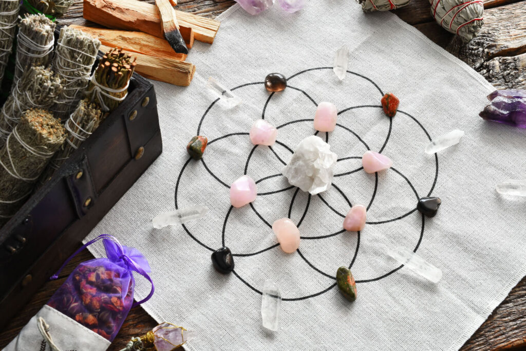 Crystal grid with various stones, amethyst, quartz, rose quartz, and others, on a light-colored cloth.  Spiritual practice.
