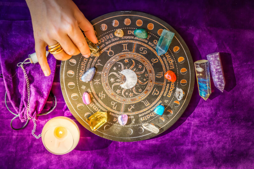 Crystal healing wheel with gemstones, moon phases, and zodiac signs.  Purple velvet background.