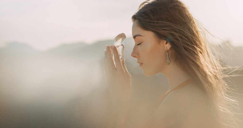 Woman holding crystal, peaceful expression.