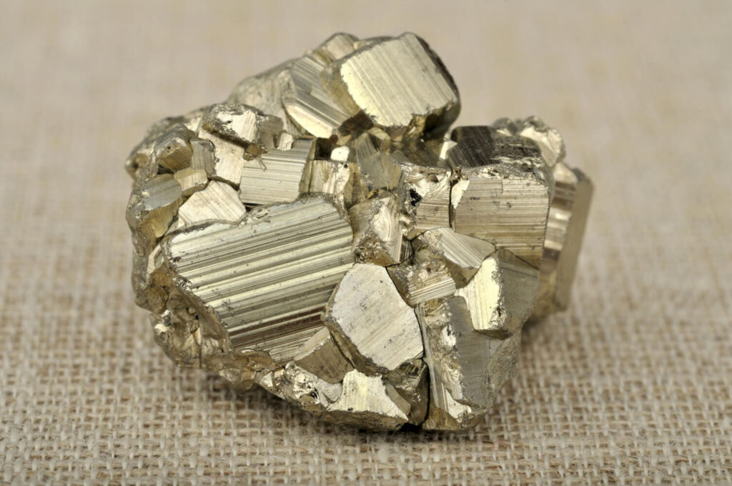Pyrite cluster, gold-colored mineral specimen on burlap.