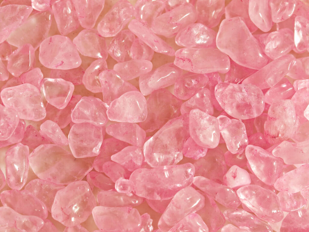 Close-up of many small, tumbled, pink quartz crystals.